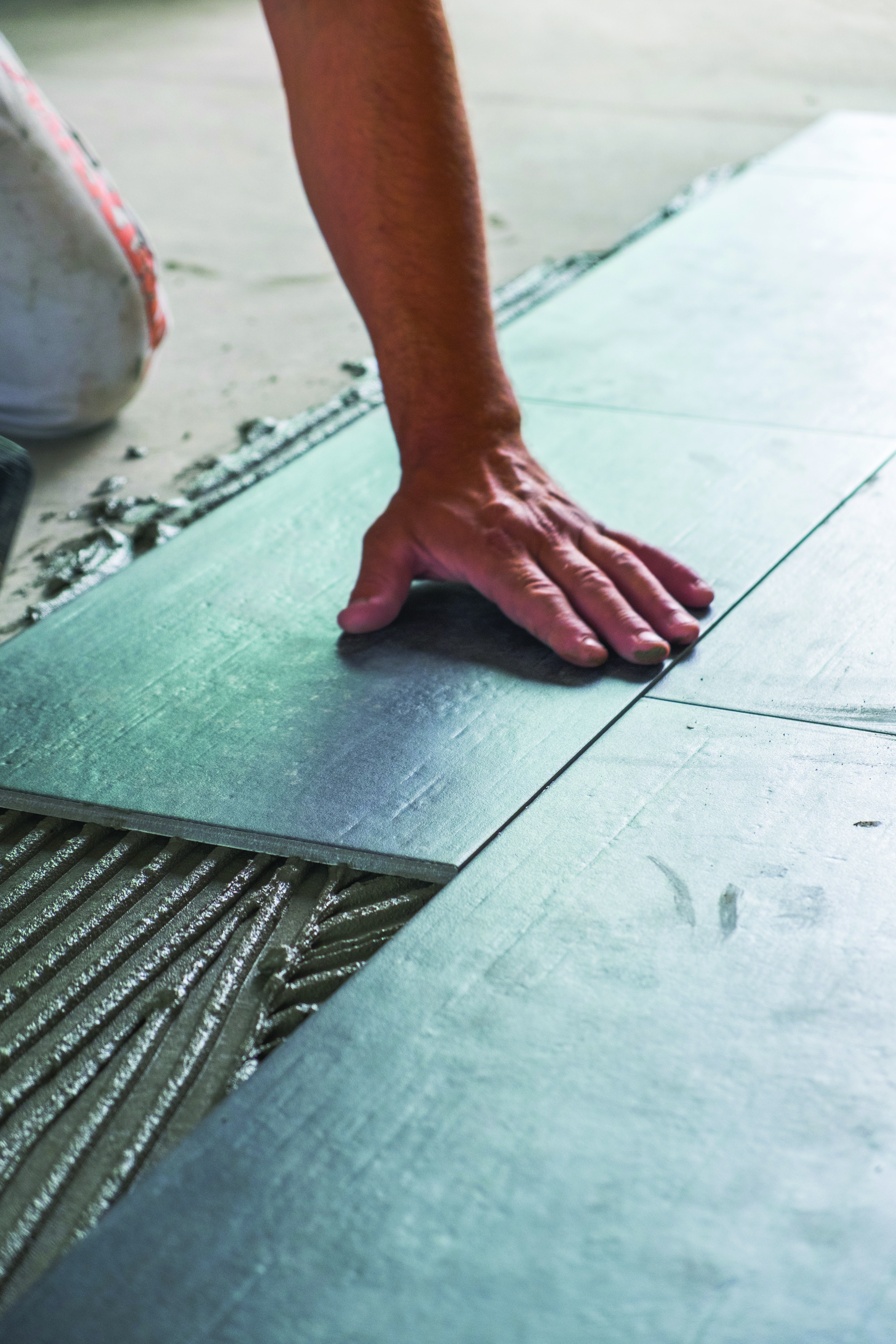 Worker installing ceramic floor tiles - LiUNA Local 183 Training Centre